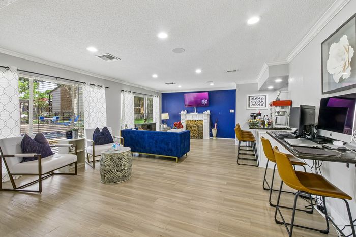 Contemporary living space featuring a vibrant blue accent wall, stylish seating area, and open-concept layout with floor-to-ceiling windows.