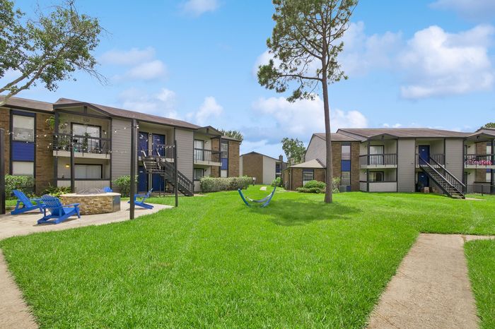 Bright and inviting apartment complex featuring lush green lawns, charming pathways, and spacious balconies perfect for relaxation.