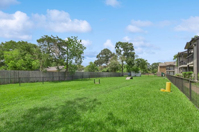 Spacious green communal area with lush grass, perfect for relaxation and outdoor activities in a charming residential setting.