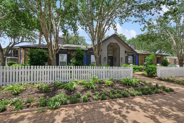 Charming suburban home with lush landscaping, a welcoming entrance, and a classic white picket fence.