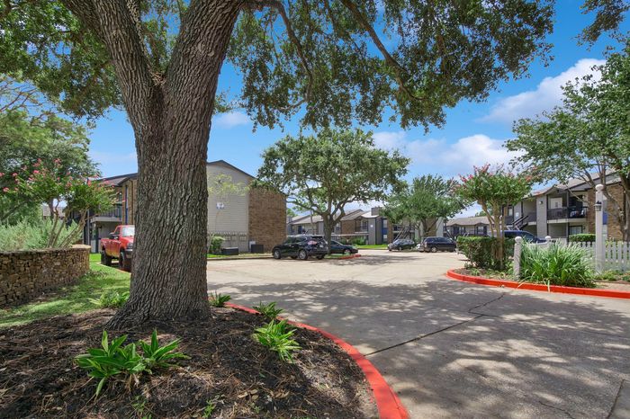 Charming apartment complex with lush greenery, spacious parking, and serene outdoor ambiance.