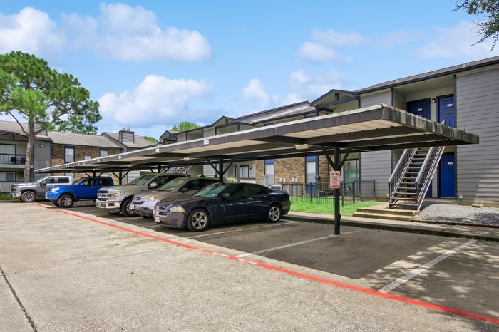 Modern apartment complex with covered parking and a serene outdoor setting, showcasing convenience and style for urban living.