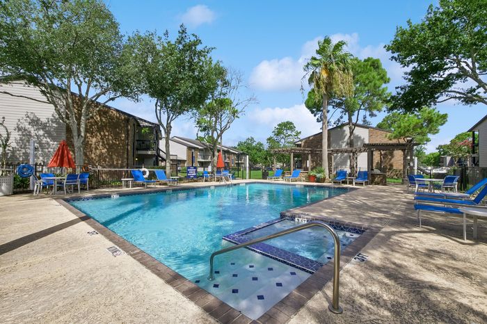 Inviting outdoor pool area surrounded by lush greenery and vibrant blue lounge chairs, perfect for relaxation and enjoyment.