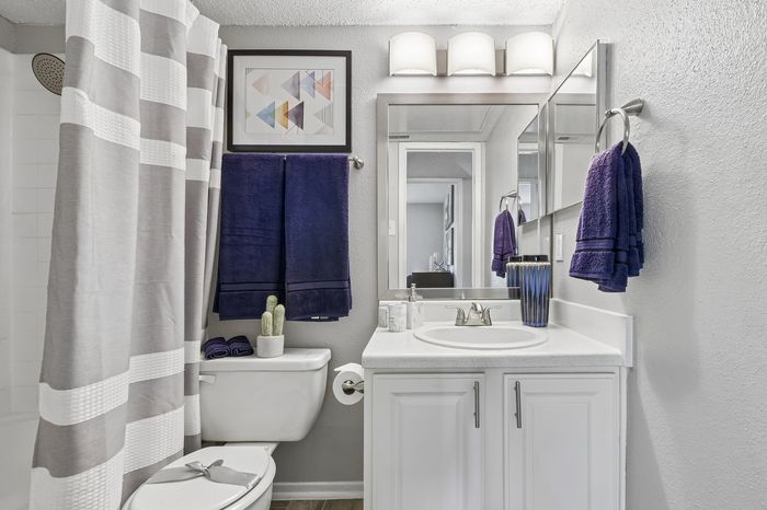 Modern bathroom featuring elegant decor with plush indigo towels, a chic striped shower curtain, and stylish minimalist accents.