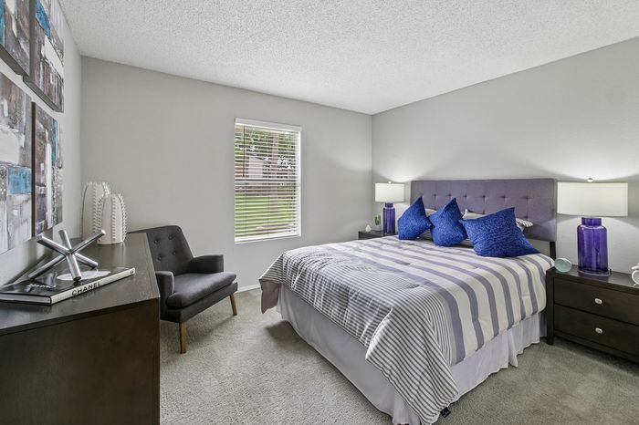 Elegant bedroom featuring a plush bed with striped bedding, vibrant decor, and natural light from a large window.