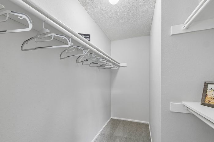 Spacious walk-in closet with ample hanging space, featuring modern white hangers and a sleek, neutral design.