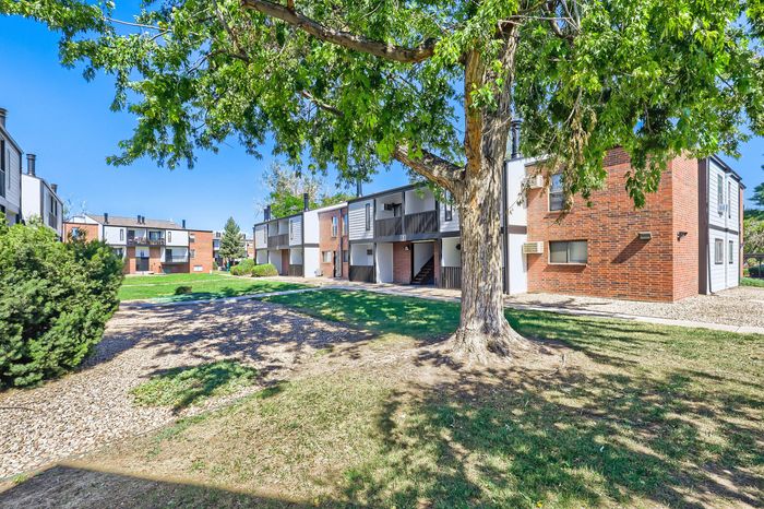 Charming residential complex with modern brick architecture, surrounded by lush greenery and mature trees, offering a serene community vibe.
