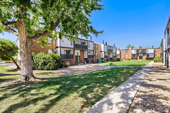 Charming apartment complex with modern architecture, featuring lush greenery and a welcoming courtyard.
