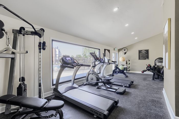 Modern fitness center featuring state-of-the-art cardio machines and weight equipment with a pool view.