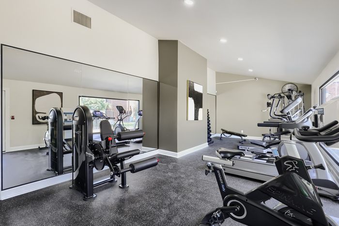 Modern fitness center within the apartment complex featuring state-of-the-art exercise equipment and mirrored walls for a spacious feel.