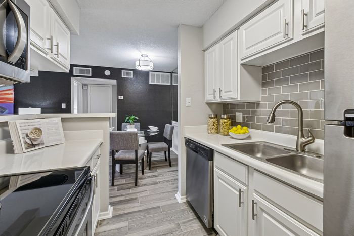 Contemporary kitchen with sleek white cabinets, stainless steel appliances, and a modern dining area with stylish decor.