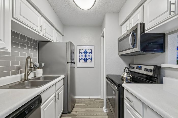 Modern kitchen with sleek stainless steel appliances, elegant subway tile backsplash, and bright white cabinetry.