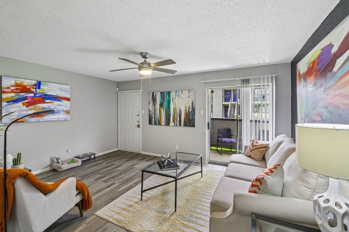 Contemporary living room featuring elegant decor, cozy seating, vibrant artwork, and a sliding glass door leading to the patio.