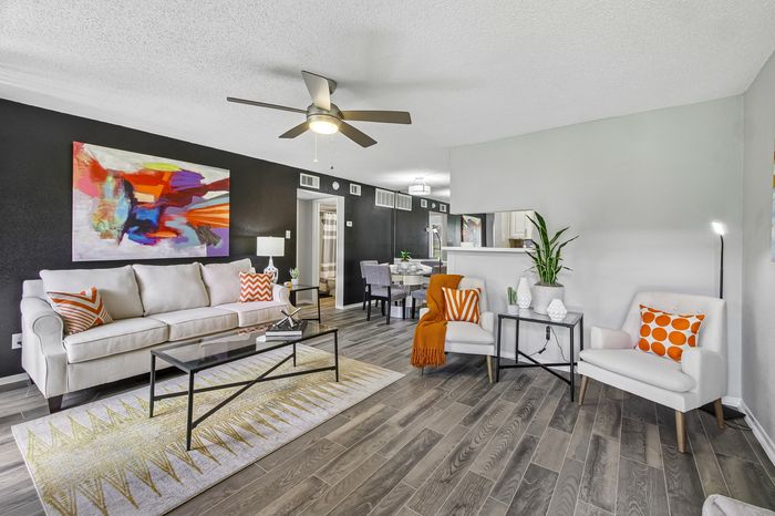 Contemporary living room with chic decor, featuring a cozy white sofa, vibrant artwork, and stylish wooden flooring.