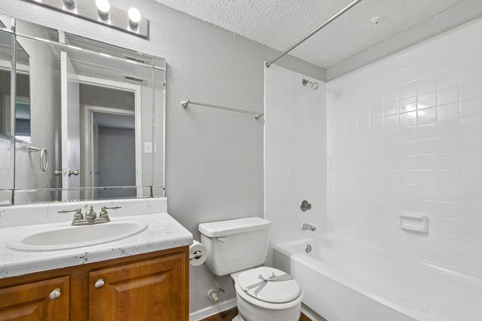 Bright and modern bathroom featuring elegant marble countertops, a sleek bathtub, and ample mirror space.