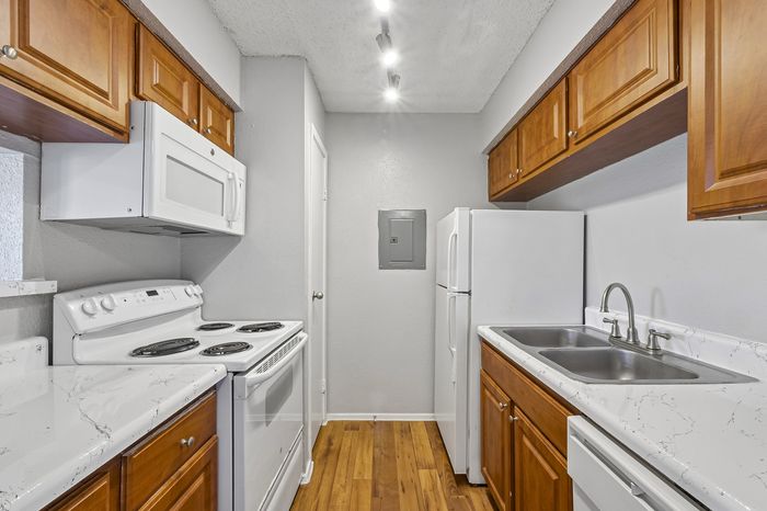 Modern kitchen with sleek white appliances, gleaming countertops, and warm wooden cabinetry offering ample storage space.