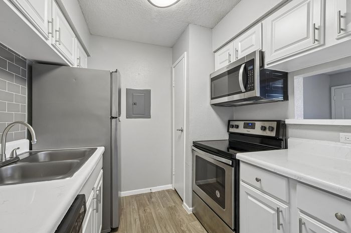 Modern kitchen with sleek stainless steel appliances, elegant white cabinetry, and a stylish gray tile backsplash.
