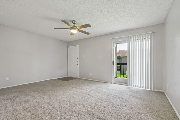 Bright and spacious living room with modern ceiling fan and large sliding door leading to a scenic balcony.