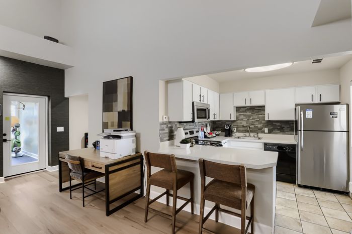 Modern open kitchen with sleek stainless steel appliances, elegant bar seating, and a cozy office nook for versatile living.