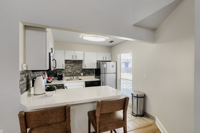 Modern kitchen with sleek countertops, stainless steel appliances, and stylish backsplash, illuminated by natural light.
