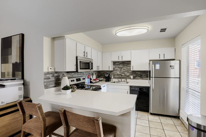 Contemporary kitchen with sleek white cabinetry, modern appliances, and a chic breakfast bar with seating.
