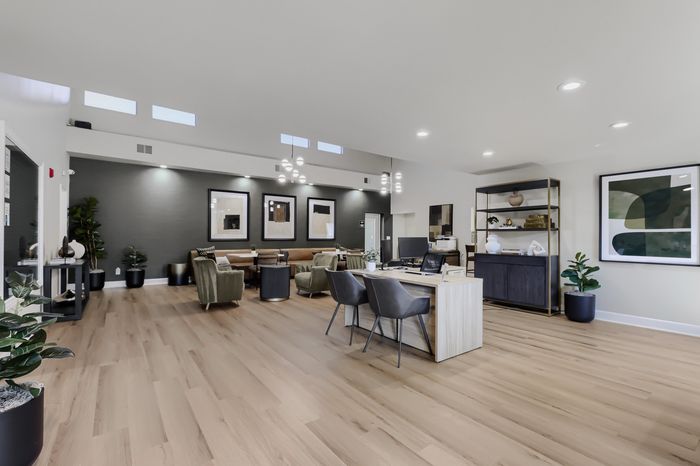 Modern and inviting living space featuring elegant hardwood floors, sleek furniture, and contemporary wall art, with ample natural light from clerestory windows.