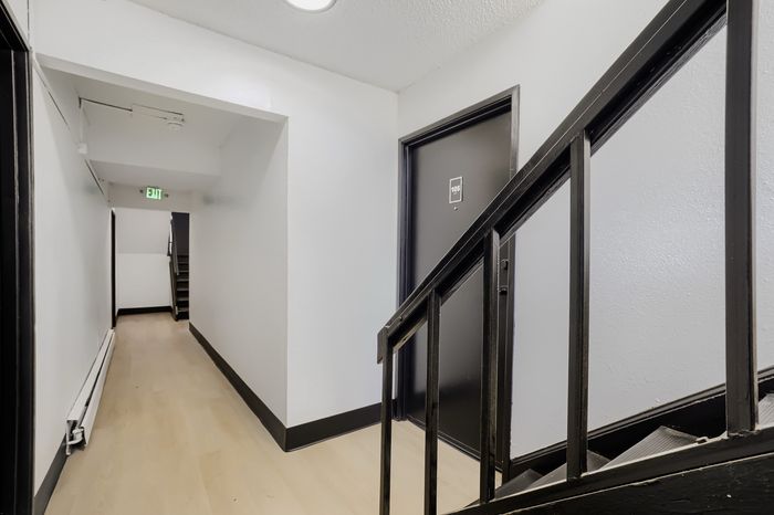 Modern apartment corridor with sleek black doors and clean architectural lines, offering a welcoming ambiance.
