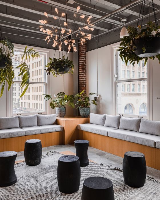 Modern urban lounge with cozy seating, vibrant greenery, and chic chandelier, ideal for relaxation in a stylish setting.