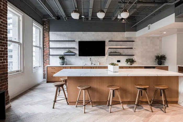 Modern kitchen featuring an elegant island with wooden stools, stylish open shelves, and chic pendant lighting in a bright urban apartment.