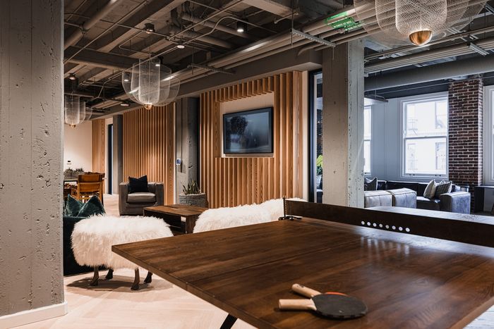 Modern apartment lounge featuring chic decor, cozy seating, and a rustic table set up for table tennis.