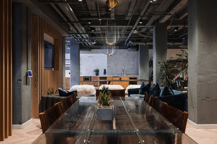 Sleek and modern apartment interior showcasing an elegant dining area with a glass-top table, plush seating, and an open-concept kitchen accented with stylish lighting and decor.