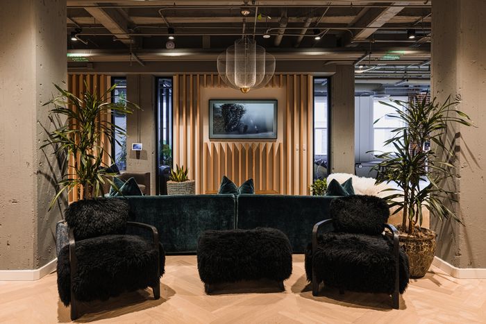 Chic apartment lounge with plush black seating, velvet sofa, modern art, and ambient lighting for a cozy urban vibe.