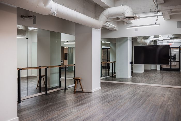 Modern, spacious studio with mirrored walls, barre, and chic industrial design, perfect for fitness or dance classes.
