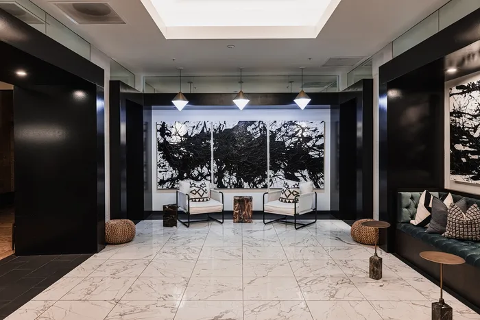 Elegant lobby with luxurious marble floors, modern seating, and striking abstract artwork under ambient lighting.