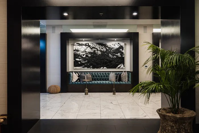 Luxurious lobby area featuring elegant marble flooring, plush seating with decorative cushions, and striking modern artwork, creating a welcoming ambiance.