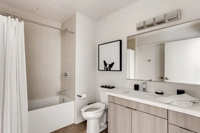 Modern bathroom with elegant tile work, sleek vanity, and stylish art piece, offering a clean and inviting space.