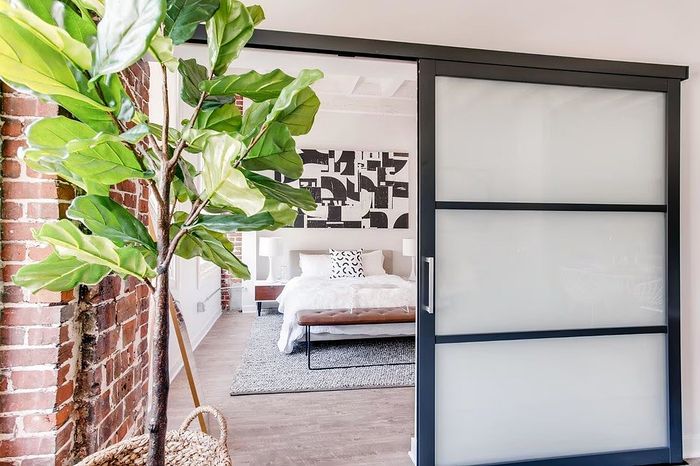 Chic bedroom with stylish decor, featuring a modern sliding glass door and an indoor leafy plant, exuding a cozy and inviting ambiance.