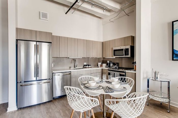 Modern kitchen with sleek appliances, elegant cabinetry, and a chic dining area set for four under stylish lighting.