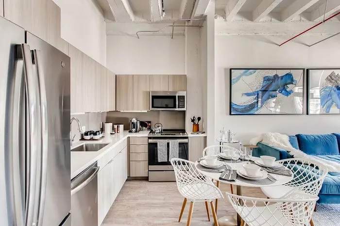 Sleek modern kitchen with stainless steel appliances, stylish dining area, and cozy living space with vibrant artwork.