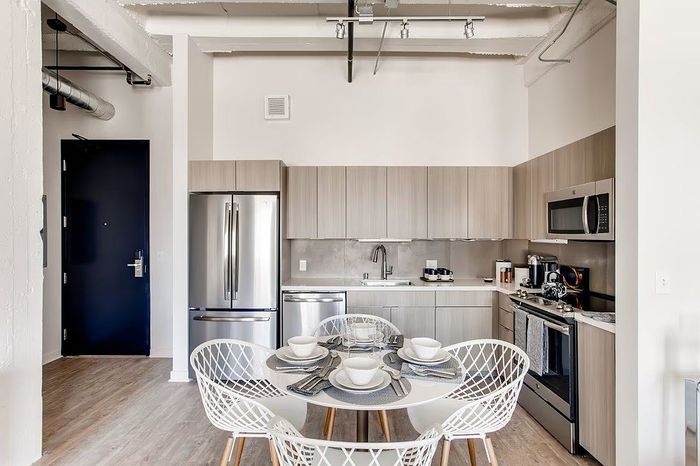 Contemporary kitchen with sleek cabinetry, stainless steel appliances, and a chic dining setup in a modern apartment.