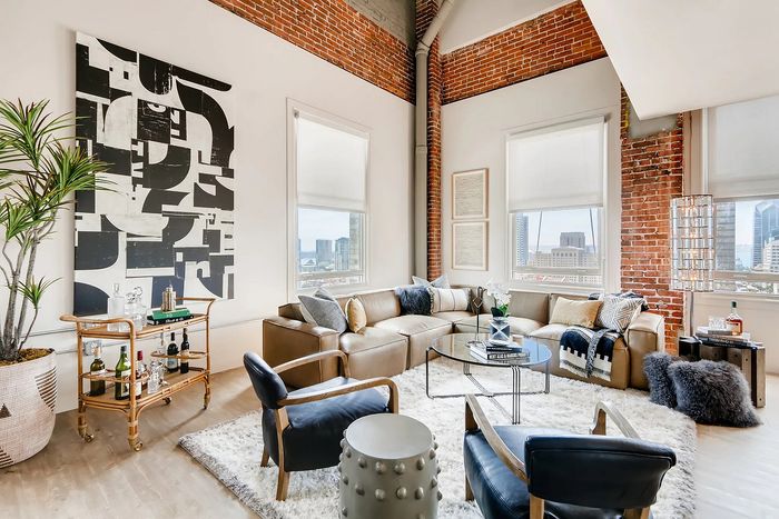 Chic urban loft with exposed brick walls, floor-to-ceiling windows, and a cozy modern living area, offering stunning city views.