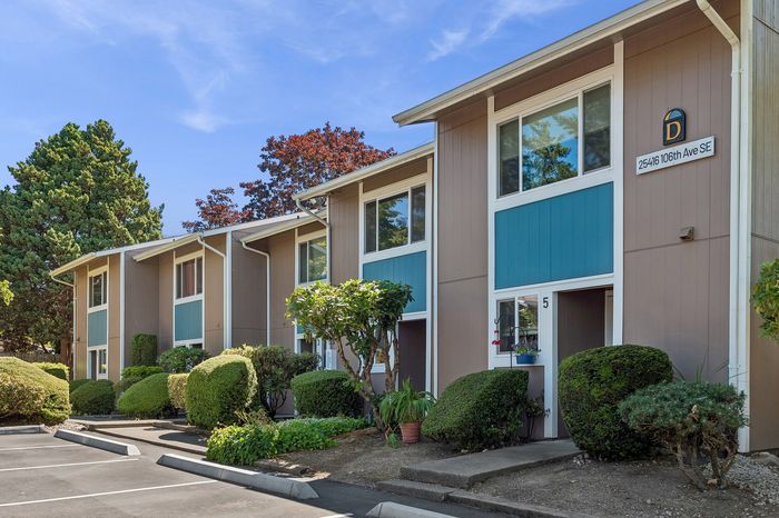 Charming apartment building with lush greenery and modern exterior design, showcasing a welcoming and serene atmosphere.