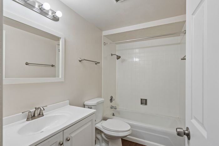 Bright and modern bathroom featuring a sleek white vanity, elegant fixtures, and a clean tile bathtub.