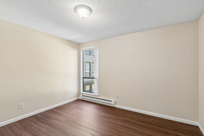 Bright and inviting room with wood flooring, modern light fixture, and a sunlit window, perfect for customization.