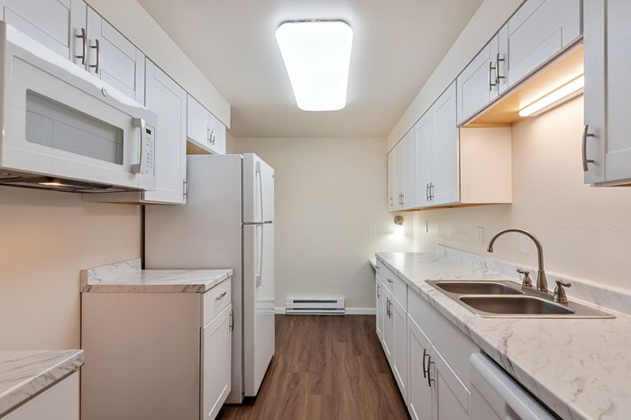 Contemporary kitchen with sleek white cabinetry, modern appliances, and elegant marble countertops, perfect for culinary creativity.