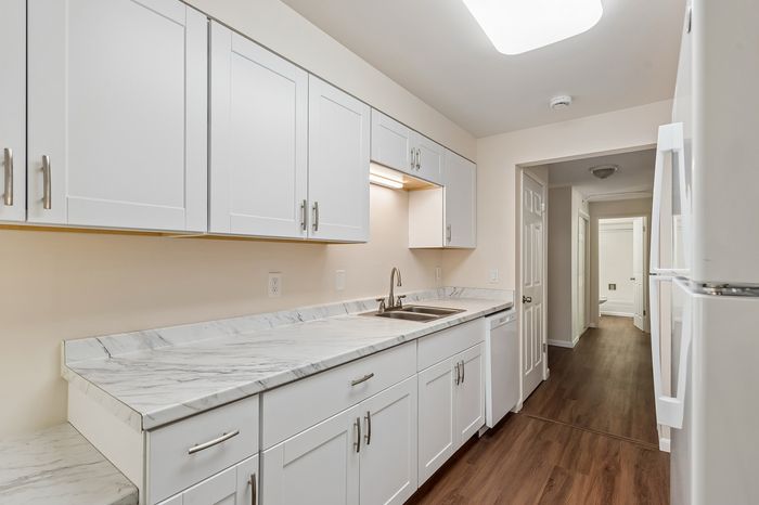 Modern kitchen with sleek white cabinets, elegant marble countertops, and sophisticated hardwood flooring.