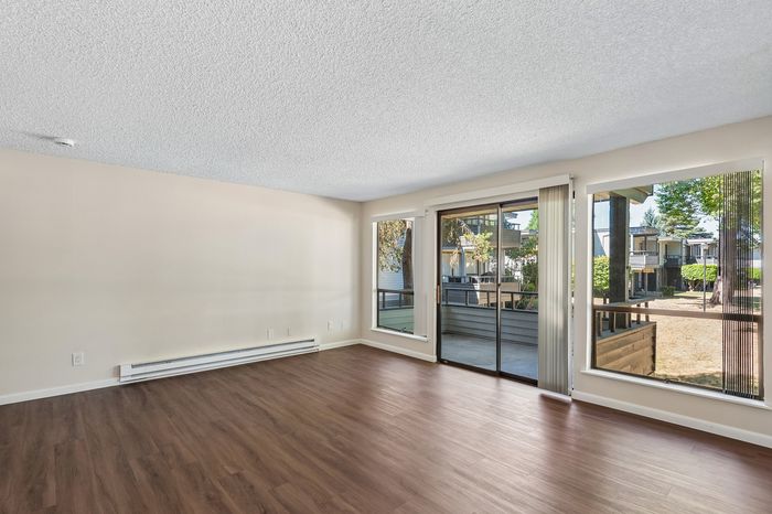 Bright and inviting living room with sleek hardwood floors and large windows offering scenic outdoor views.