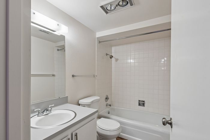 Bright and modern bathroom with elegant white fixtures, a sleek vanity, and a spacious shower-tub combination.