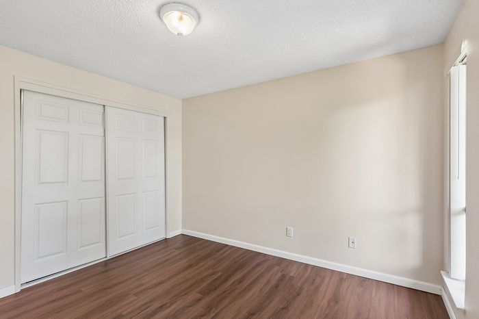 Bright bedroom with elegant wood flooring and spacious closet, perfect for a tranquil retreat.