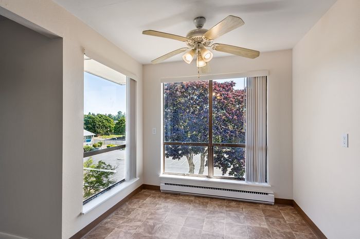 Bright apartment corner with large windows offering scenic views of lush greenery and a spacious layout.